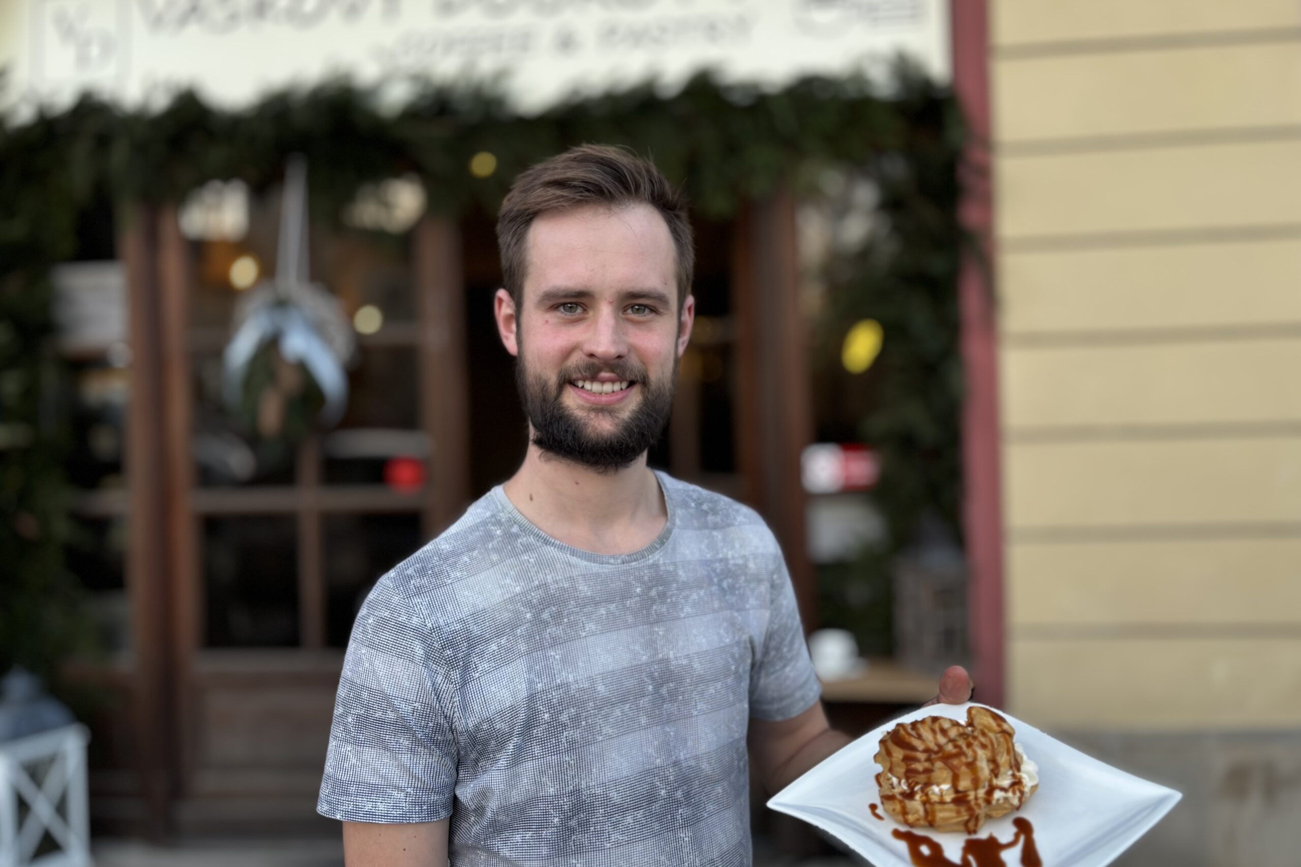 Před kavárnou Vaškovy dobroty stojí s úsměvem majitel Vašek, který za vším stojí